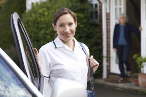 a portrait of a caregiver smiling in front of a car